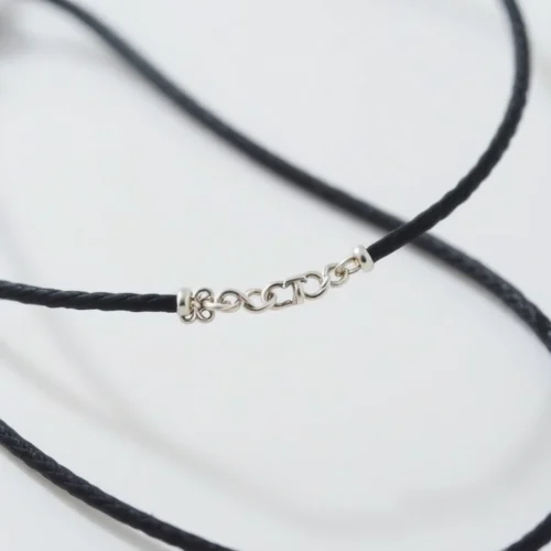 Sleek silver bracelet on a string, highlighting intricate details and high-quality craftsmanship.